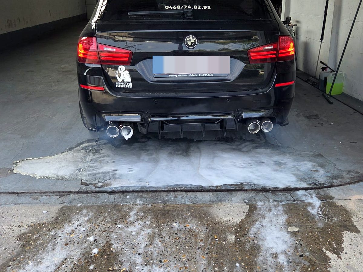 Zwarte BMW met Monkey Mechanics kentekenhouder in de werkplaats